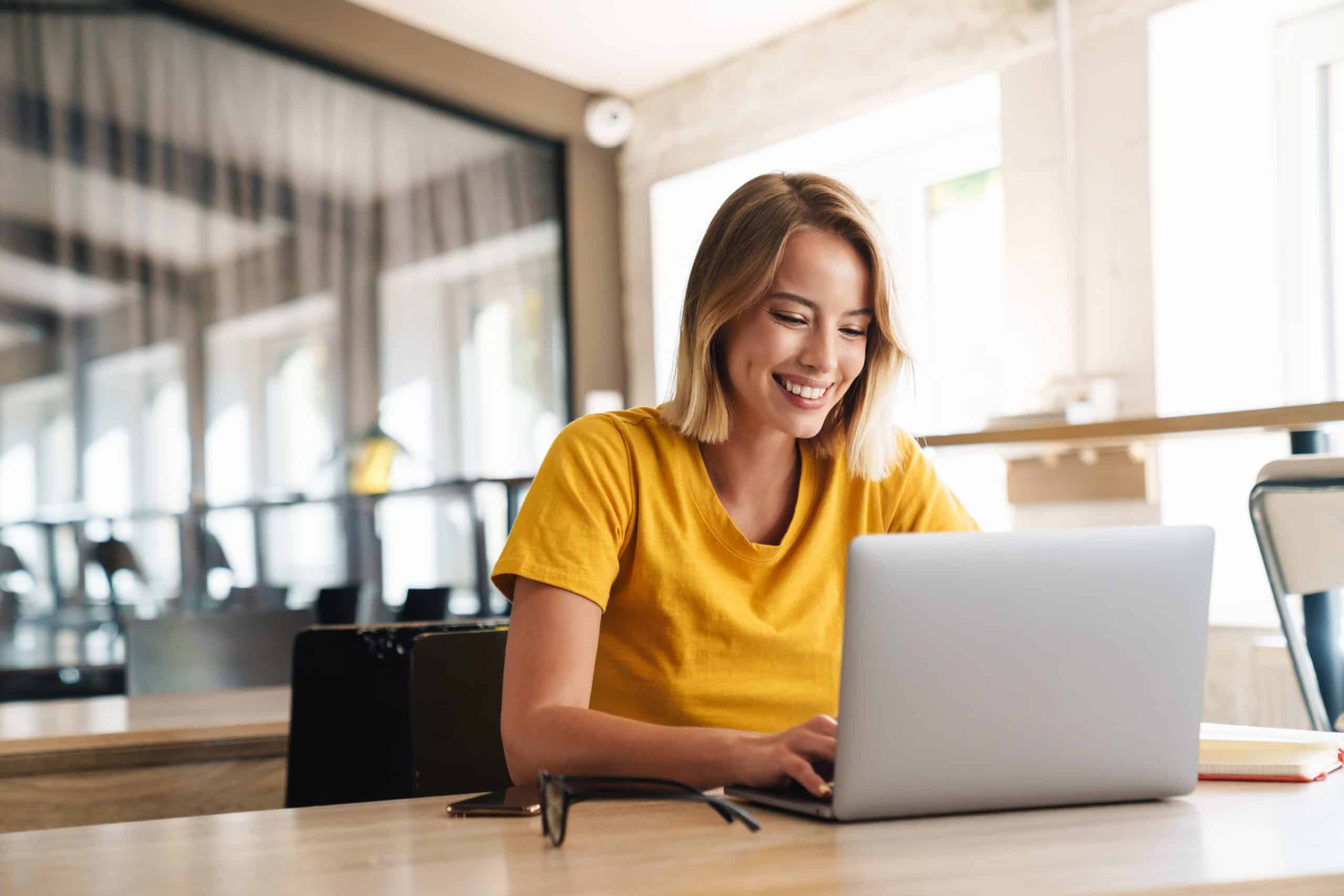 Photo of joyful nice woman using laptop and smiling while sittin