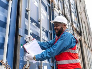 Photo of a black african engineer using his hands trying to open the chain on a container in a shipping containers yard